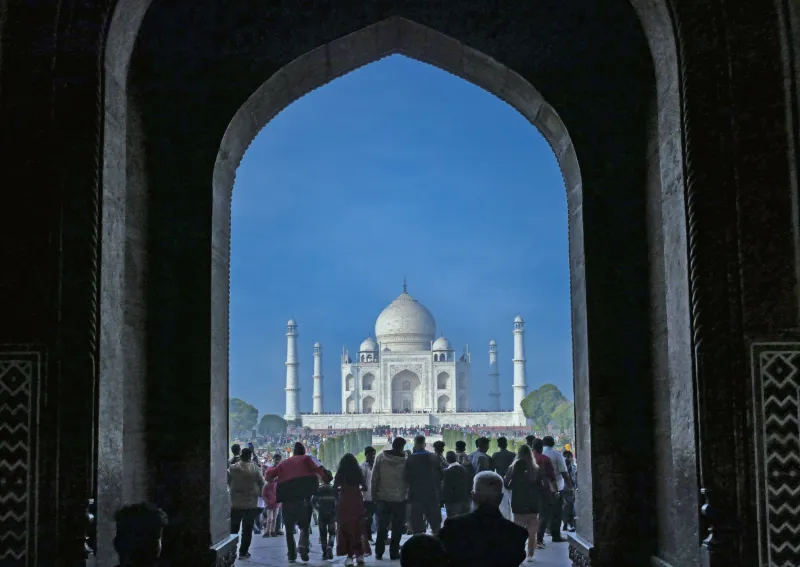 Taj Mahal i Indien sett genom valvbåge med besökare i förgrunden