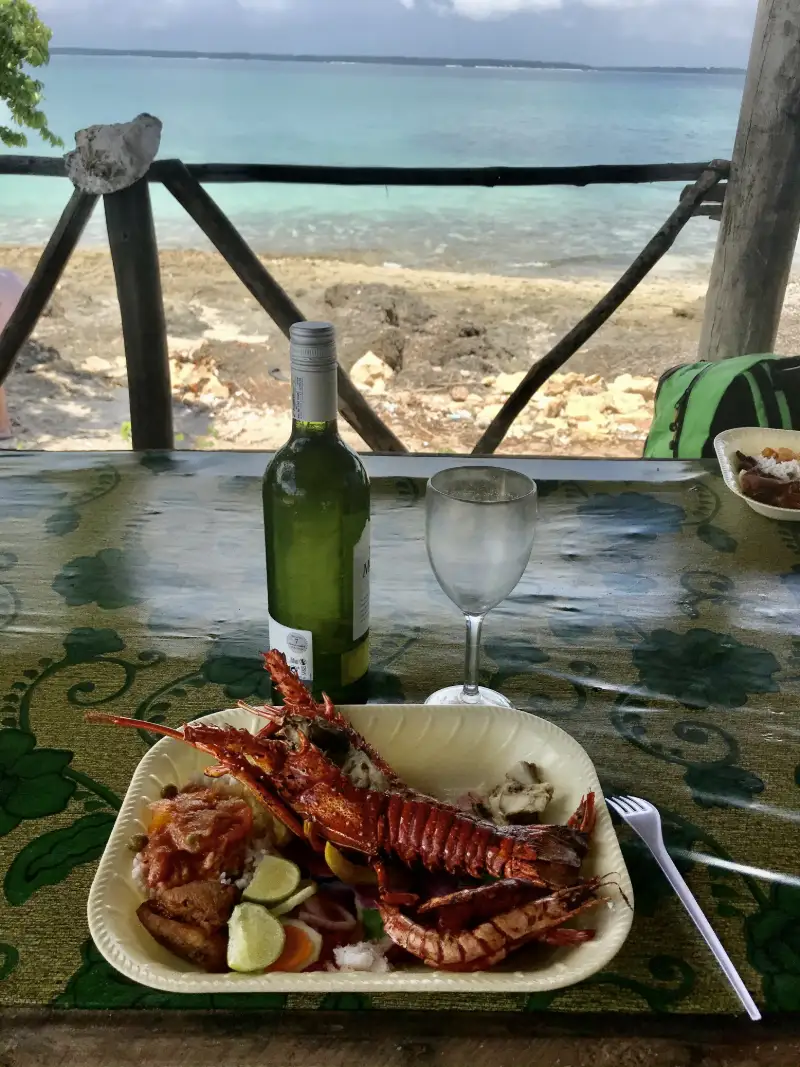 Lunch med hummer och vitt vin vid stranden med utsikt över havet på Zanzibar