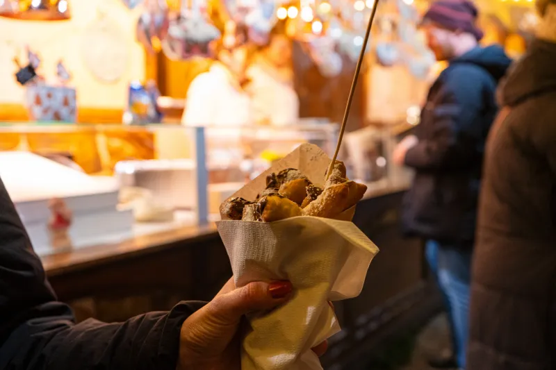 Hand som håller varm street food på julmarknad