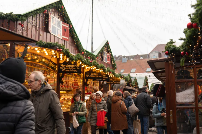 Julmarknadsstånd med ljusslingor och besökare i Lübeck