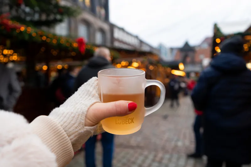 Hand som håller varm glühwein på julmarknad i Lübeck