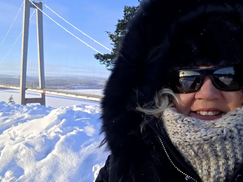 Resenär vid Högakustenbron i vinterlandskap under bussresa genom Norrland
