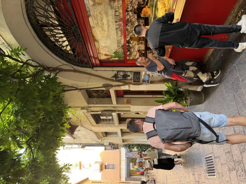 Resenärer promenerar genom en charmig gränd med restauranger och uteserveringar i Italien