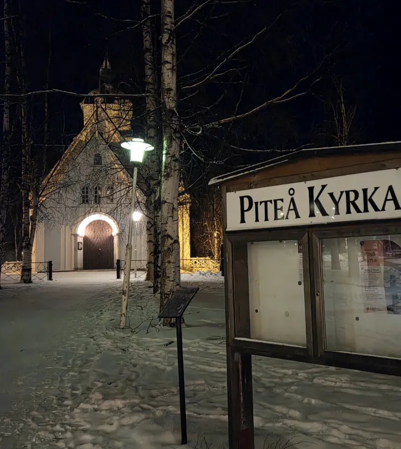 Piteå kyrka och vinterlandskap upplyst i kvällsmörker