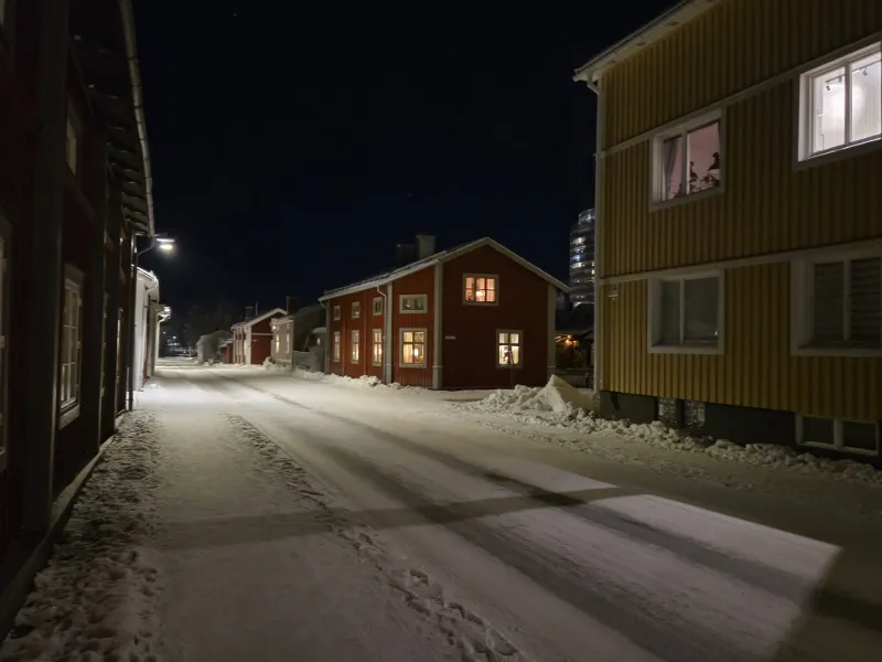 Snötäckt gata och trähus i centrala Piteå under vinterkväll