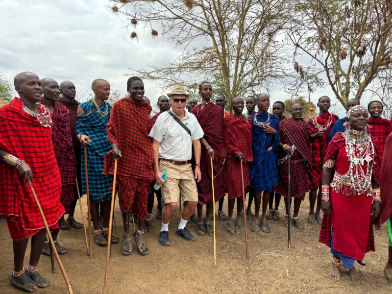 Resenär tillsammans med massajer i traditionella kläder under besök i by i Afrika