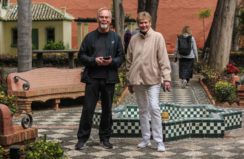 Två resenärer promenerar i grönskande innergård