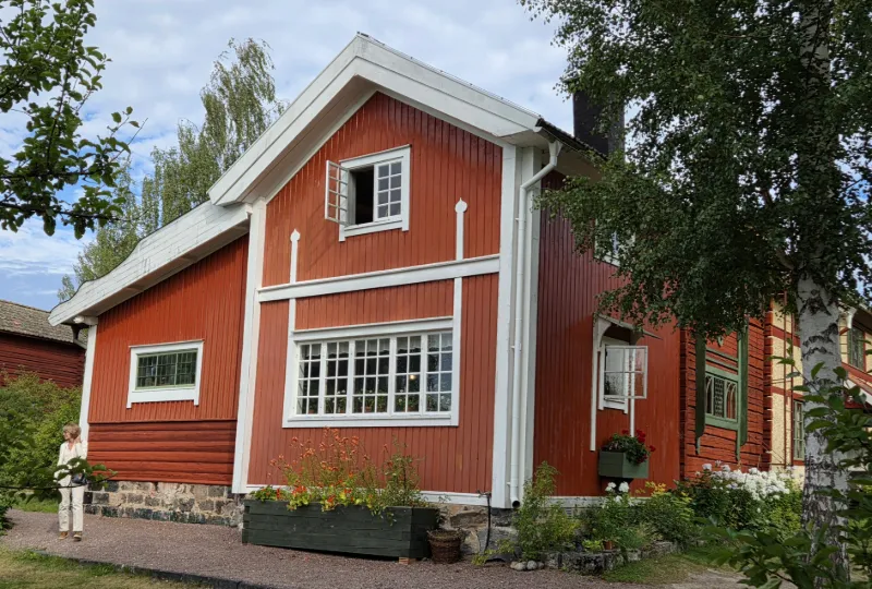 Traditionell rödmålad gårdsbyggnad med vita snickerier.