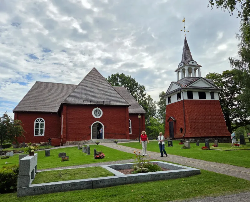 Kyrkan med sin karakteristiska röda träfasad och fristående klockstapel.