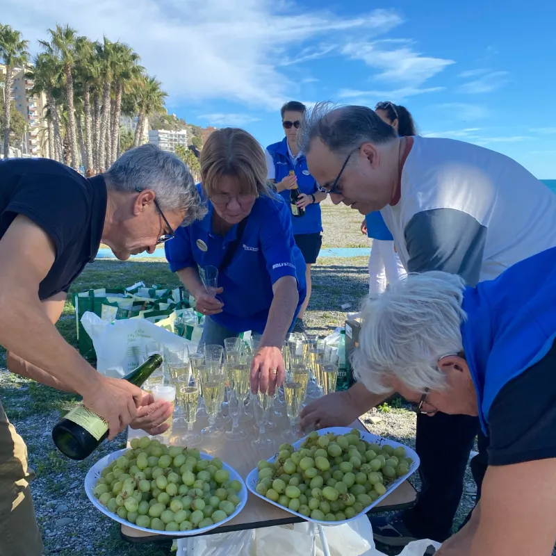 Resenärer serverar mousserande vin och druvor under strandaktivitet i Spanien