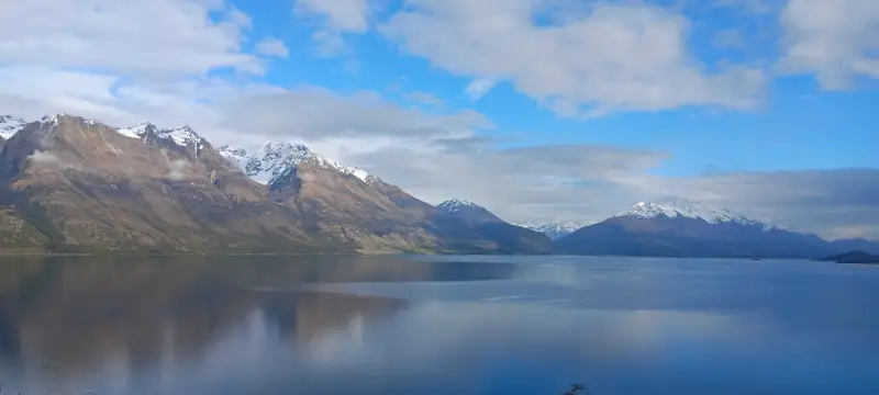 Snötäckta berg och spegelblank sjö i det dramatiska landskapet på Nya Zeeland