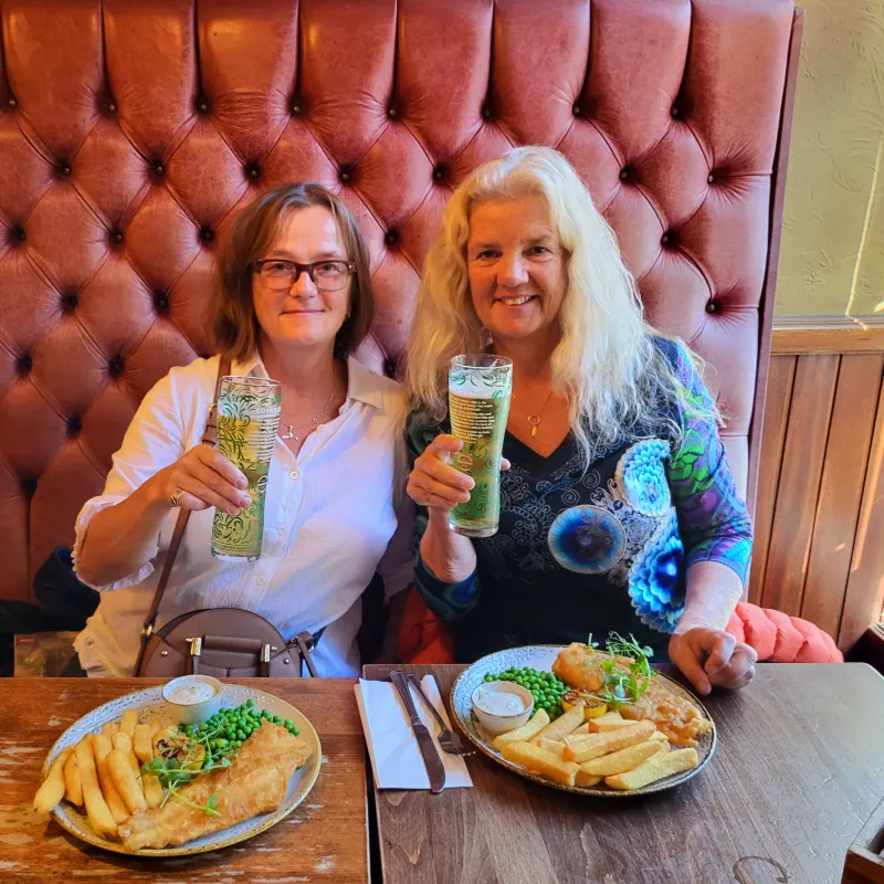 Anne och Elisabet njuter av fish and chips och öl på pub under resa i Skottland
