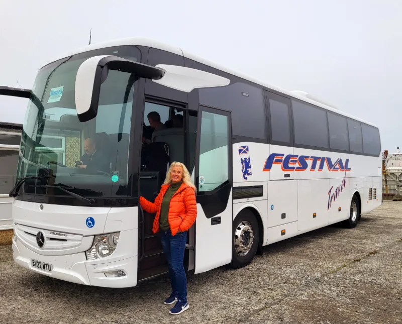 Resenär står vid turistbuss från Festival Tours under rundresa i Skottland