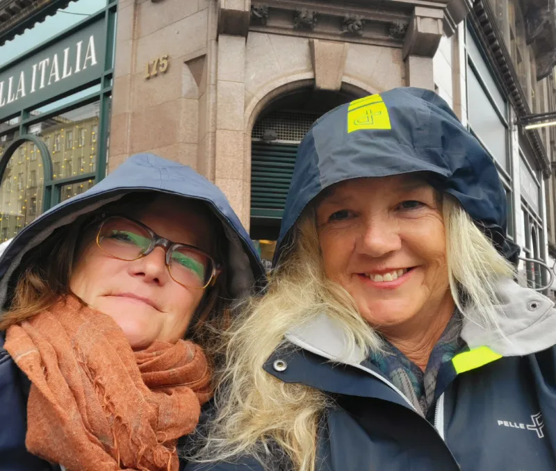 Två resenärer i regnkläder under stadsbesök i Edinburgh