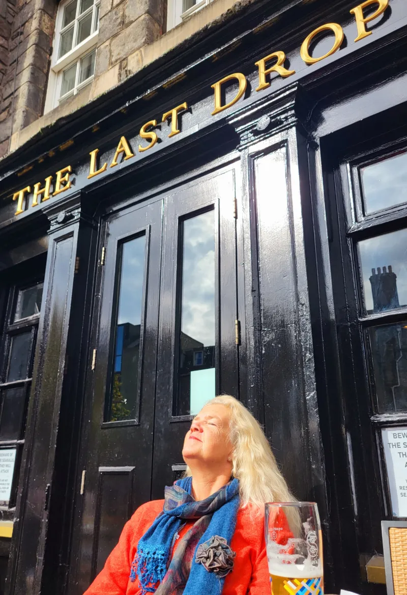 Resenär njuter av solen utanför puben The Last Drop i Edinburgh