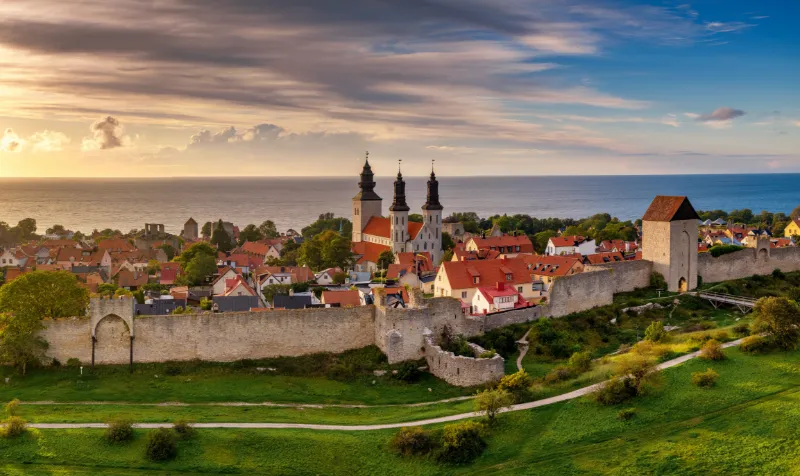 Visby ringmur och historiska stadskärna på Gotland i solnedgång med havet i bakgrunden.