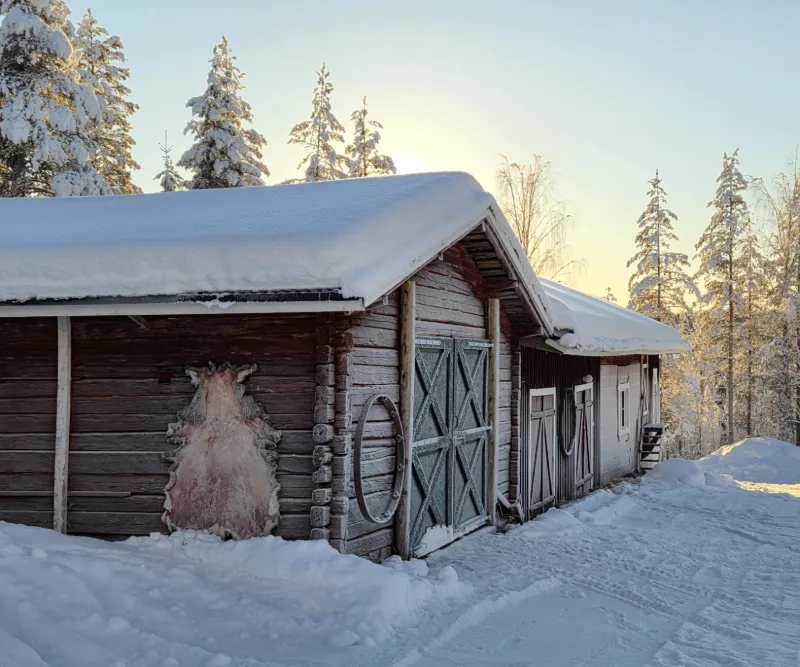 Snötäckt stuga i vinterlandskap i norra Sverige