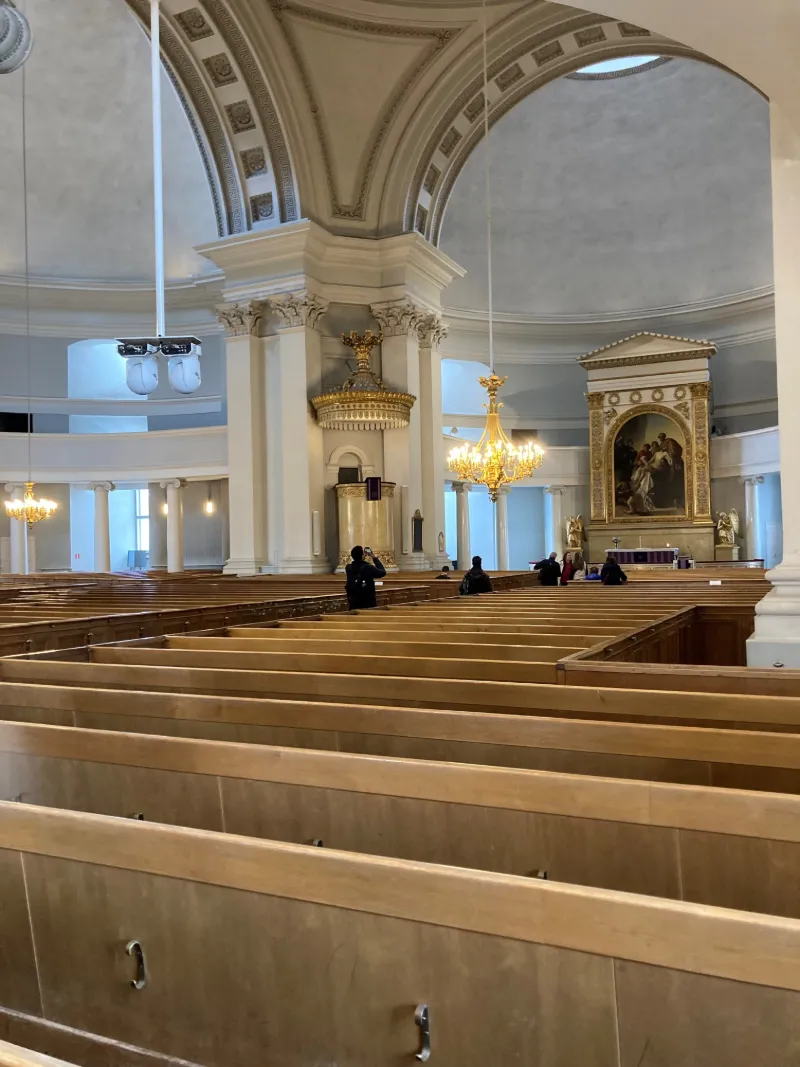 Vacker kyrkointeriör med höga valv och ljuskronor i Helsingfors