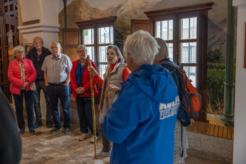 Resesällskap lyssnar på guide under rundtur i historisk byggnad