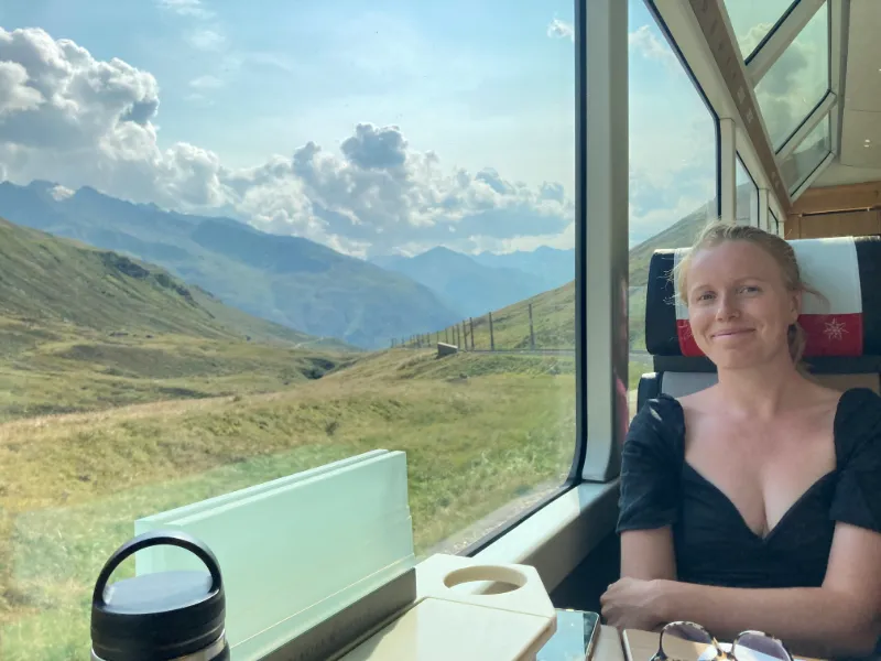 Utsikt från panoramatåg över schweiziska alper och gröna vidder