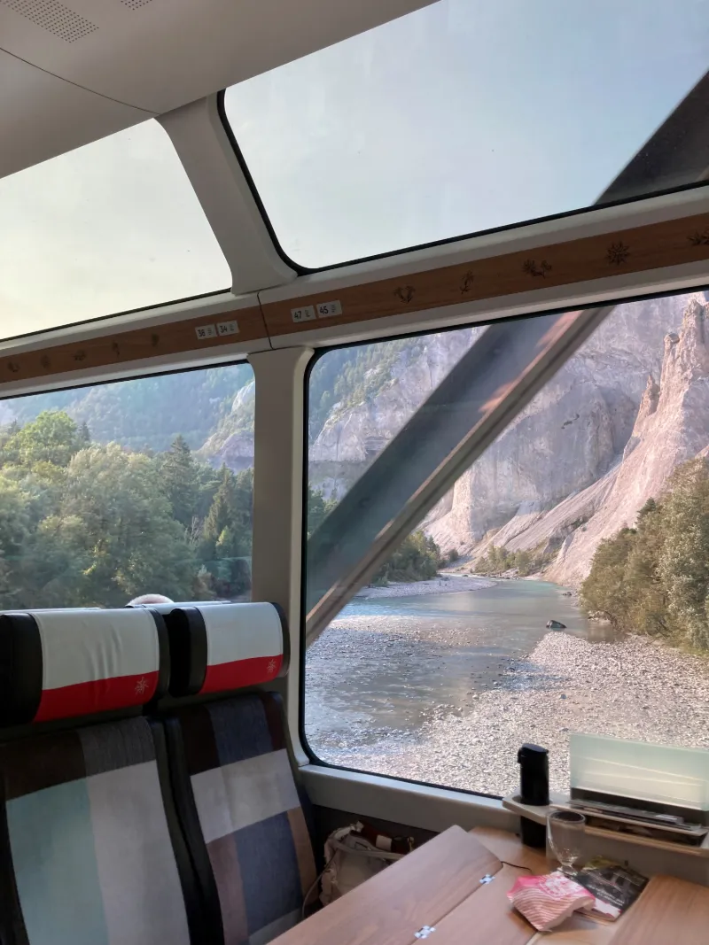 Tågresa genom dramatiskt bergslandskap och dalgång