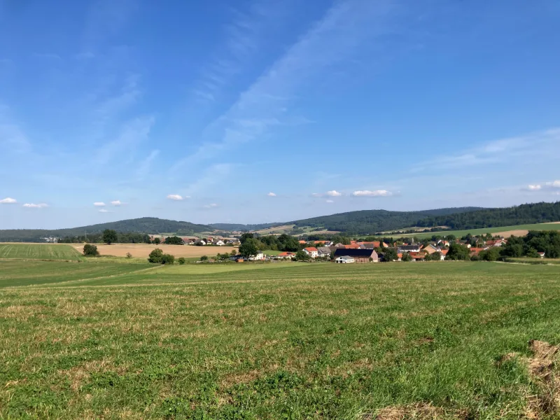 Böljande landskap och små byar under klarblå himmel