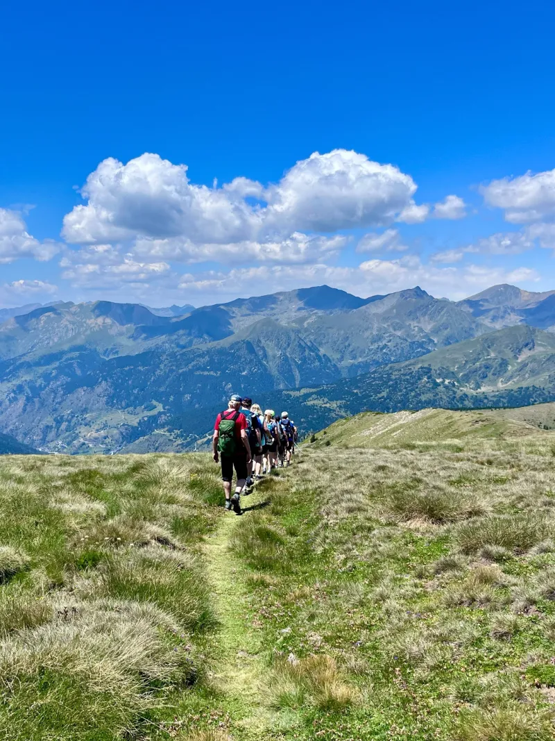 Vandringsgrupp på bergsrygg med panoramautsikt över majestätiska berg