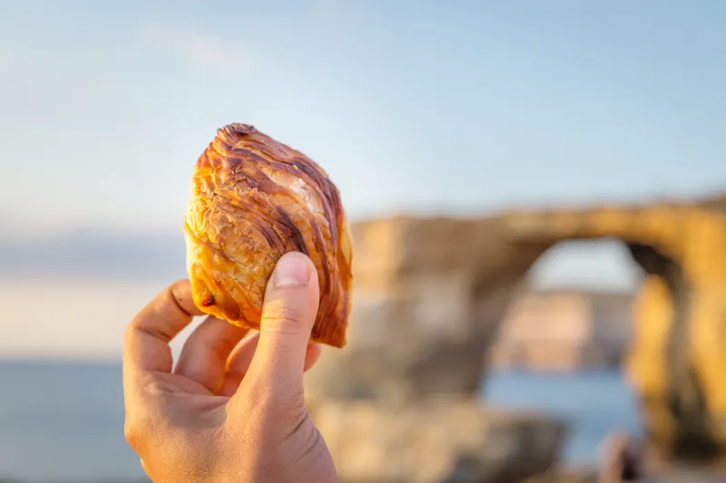 Tradisjonell pastizzi foran Maltas ikoniske Azure Window.