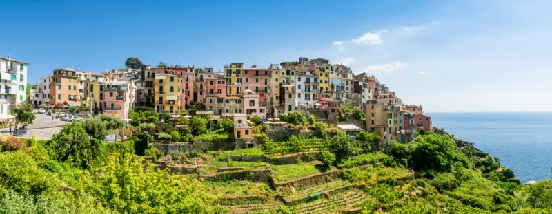 Corniglia på en höjd ovanför havet med terrassodlingar och utsikt över Cinque Terres kustlandskap.