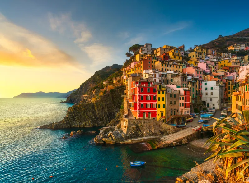 Färgglada hus och kustklippor i Riomaggiore vid solnedgång i Cinque Terre.