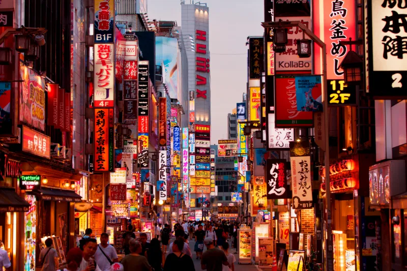 Lysende neonskilt i en travel gate i Tokyo.