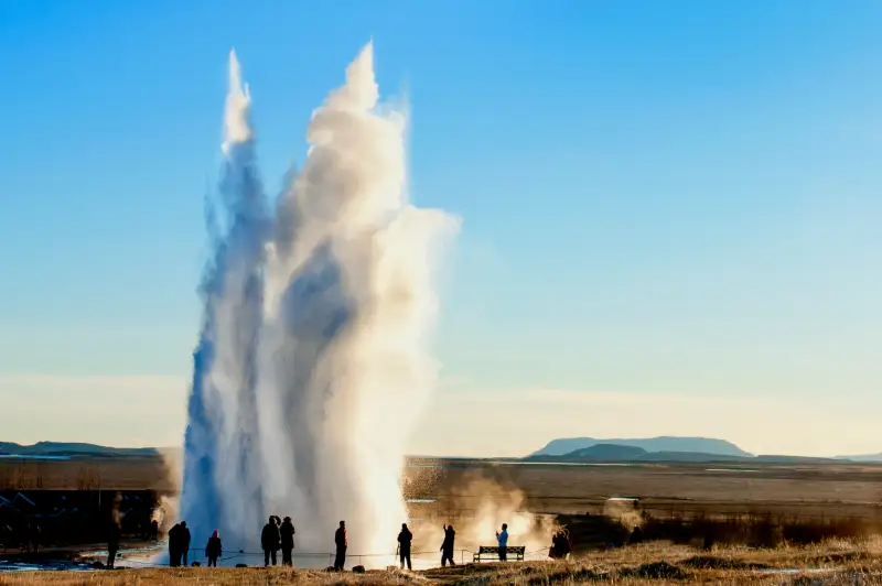 Gejsern Strokkur sprutar vatten högt upp i luften.