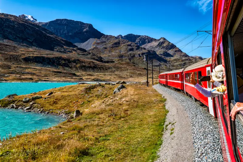 Rött panoramatåg genom Schweiz alplandskap.