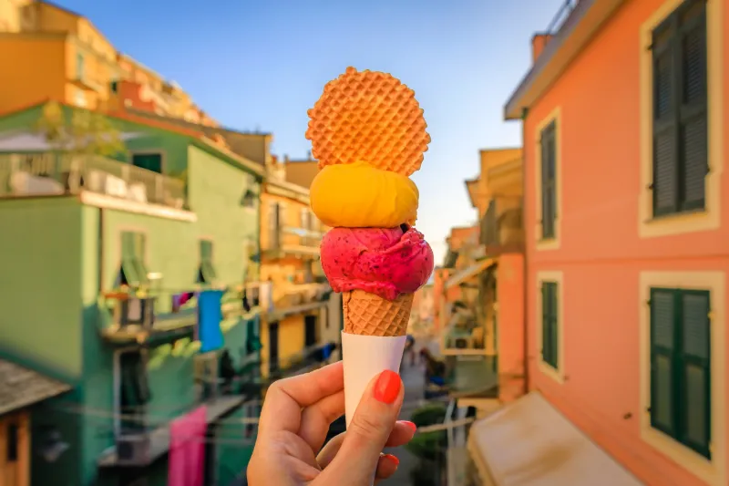 Glass framför färgglada hus i en av Cinque Terres charmiga kustbyar i Italien.