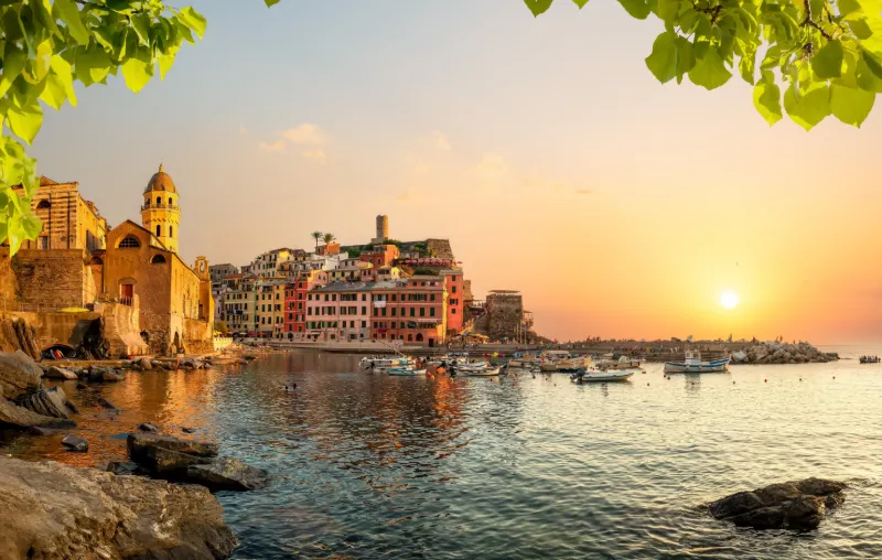 Solnedgång över Vernazzas hamn med färgglada byggnader och båtar i Cinque Terre.