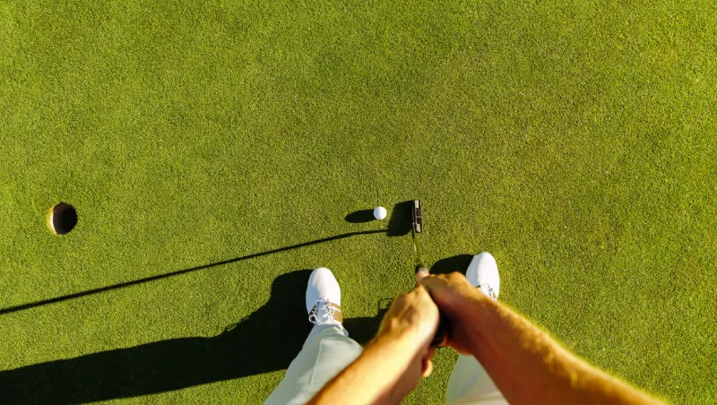 Person på golfbana som ska putta en golfboll