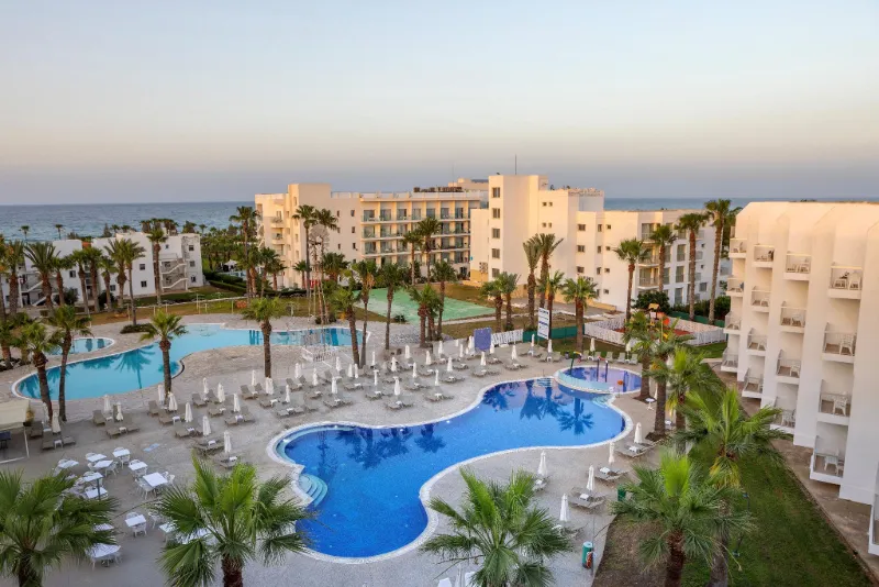 Hotellresort med pooler, palmer och havsutsikt vid Cyperns kust.