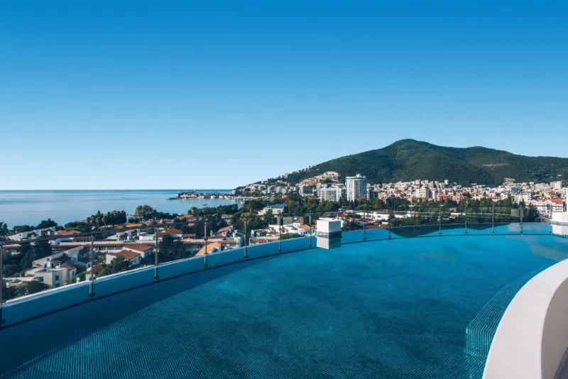 : Infinitypool på takterrass med utsikt över Budva, havet och de omgivande bergen.