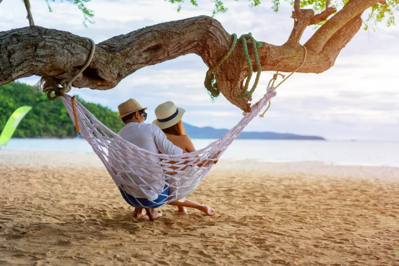 Par som sitter i hängmatta på en strand i Thailand och njuter av utsikten