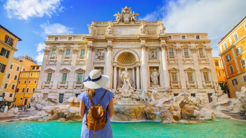 Resenär framför Fontana di Trevi i Rom under solig dag