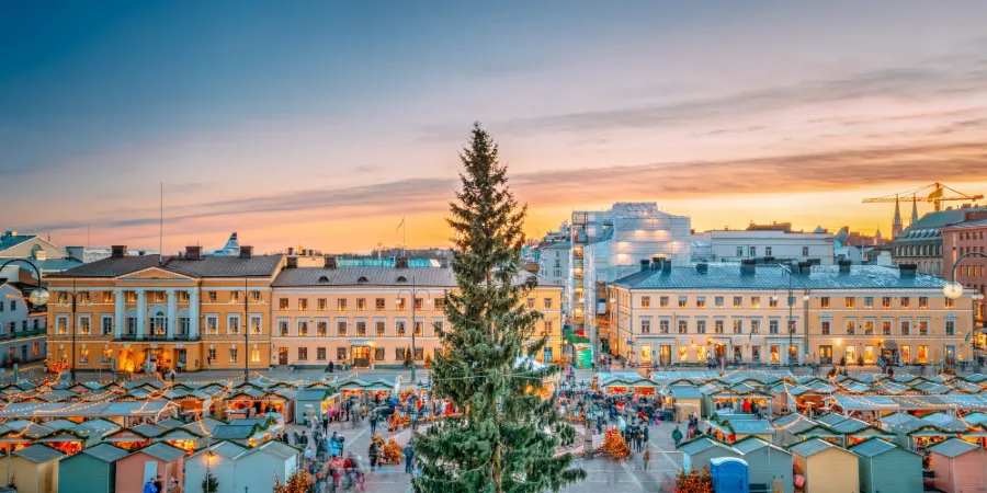 Julmarknad på Senatstorget i Helsingfors med stor julgran och upplysta byggnader vid kvällstid
