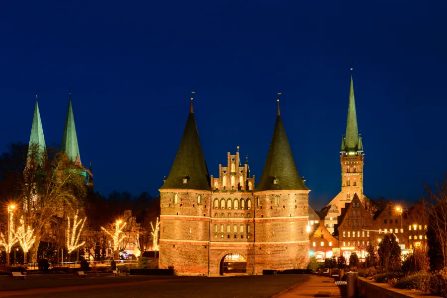 Julmarknad i Lübeck med upplysta marknadsstånd framför Holstentor i Tyskland